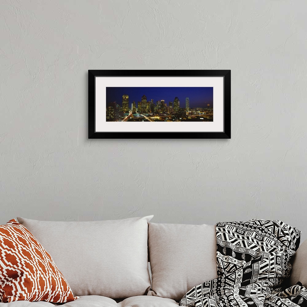 A bohemian room featuring Panoramic photograph showcases the busy skyline of Dallas, Texas as it shines at night.