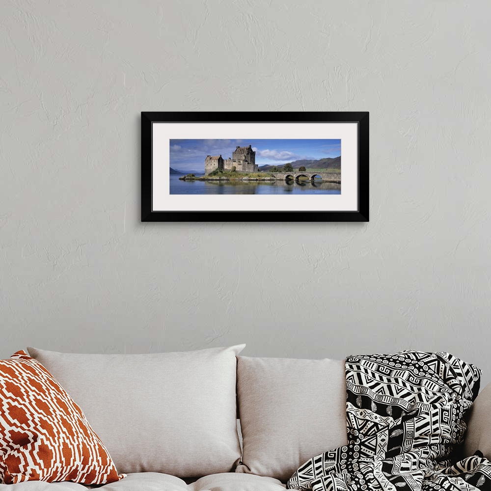 A bohemian room featuring Panoramic photograph of a bridge over Loch Duich, leading to a large, old castle on Eilean Donan ...