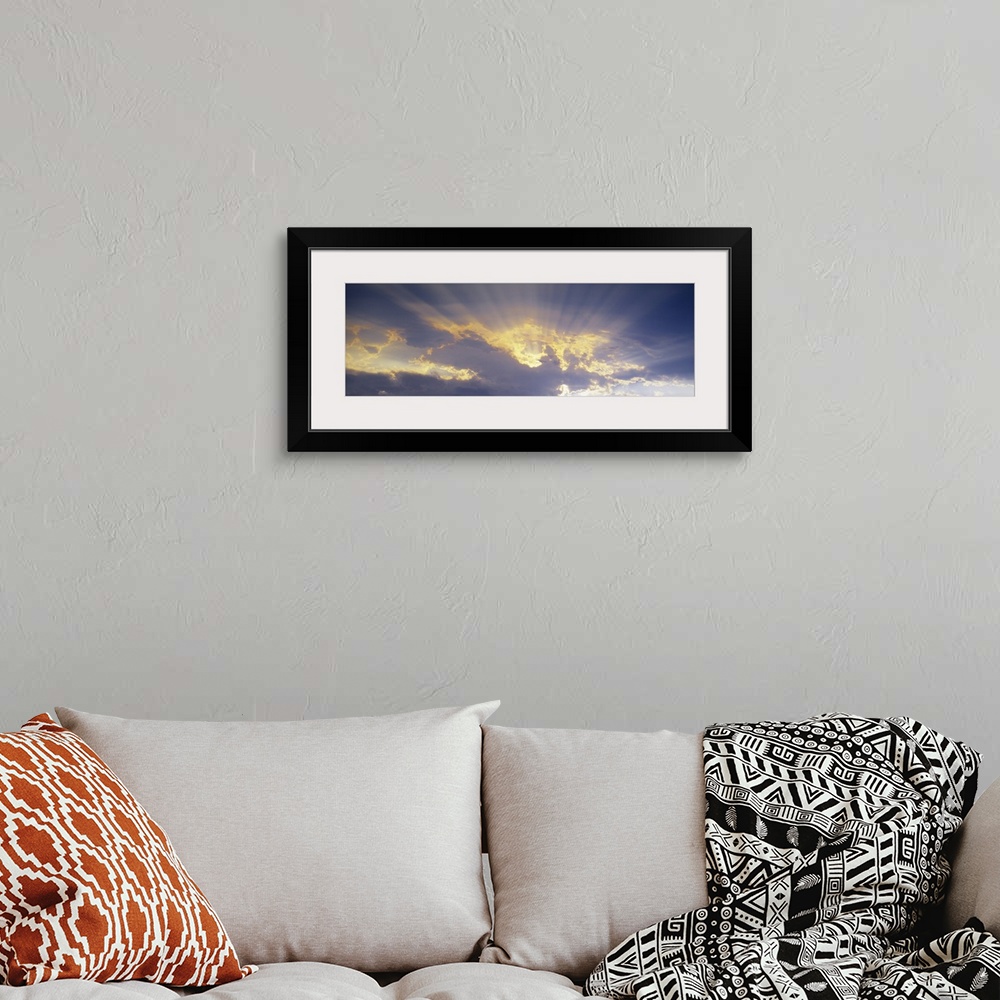 A bohemian room featuring A horizontal canvas photo of sun rays shining through clouds.