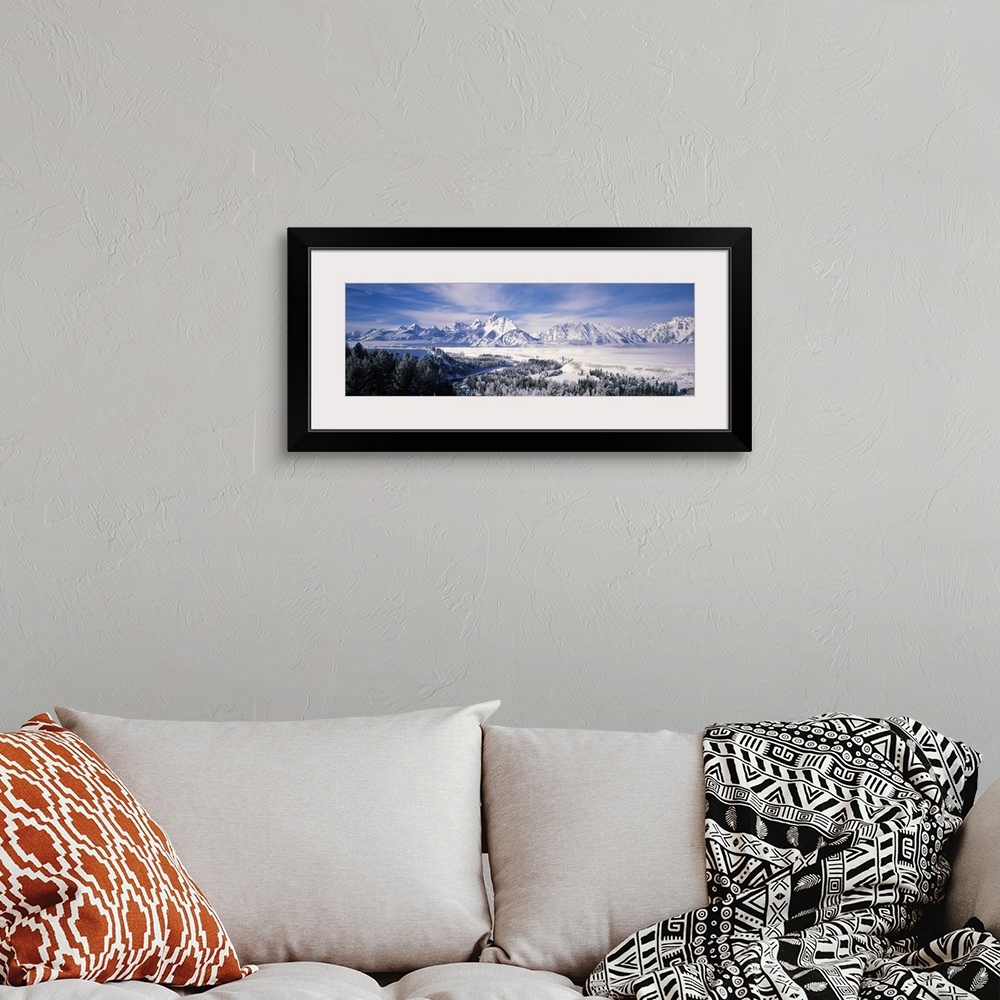 A bohemian room featuring Panoramic photograph of snow covered mountains with forest in the foreground under a cloudy sky .