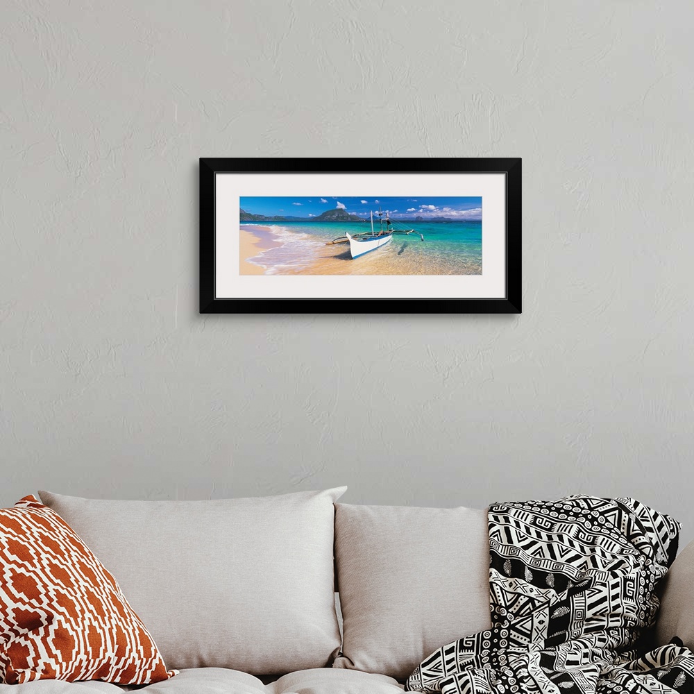 A bohemian room featuring A panoramic photograph of a tropical beach with mountains and island in the background with a boa...