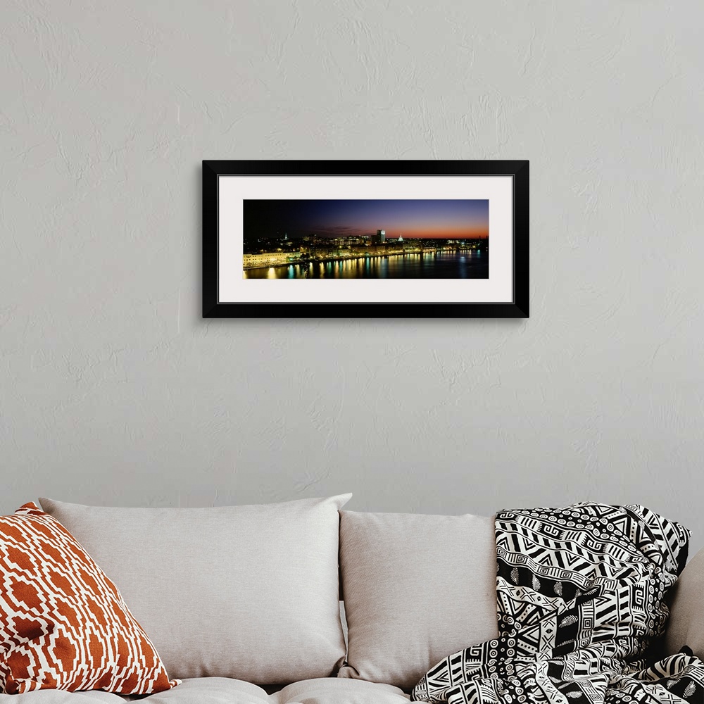 A bohemian room featuring Panoramic photograph of lit up skyline and waterfront at sunset under a colorful sky.