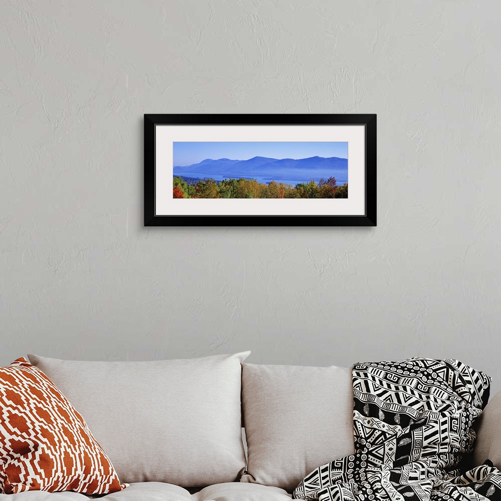A bohemian room featuring Panoramic photograph on a large wall hanging of the tops of autumn trees in front of Lake George,...