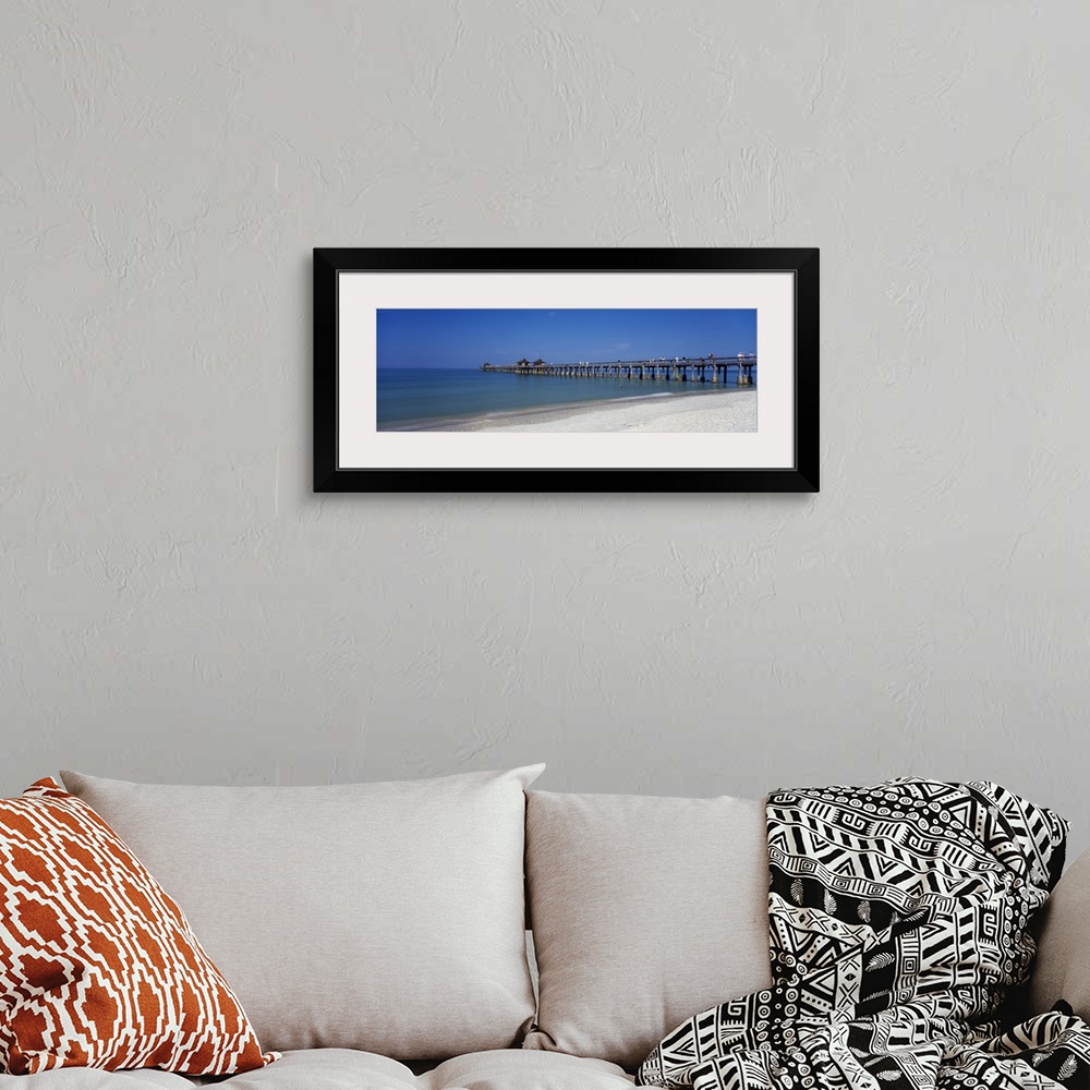 A bohemian room featuring This wall art is a panoramic photograph of a beach board walk extending into the ocean.