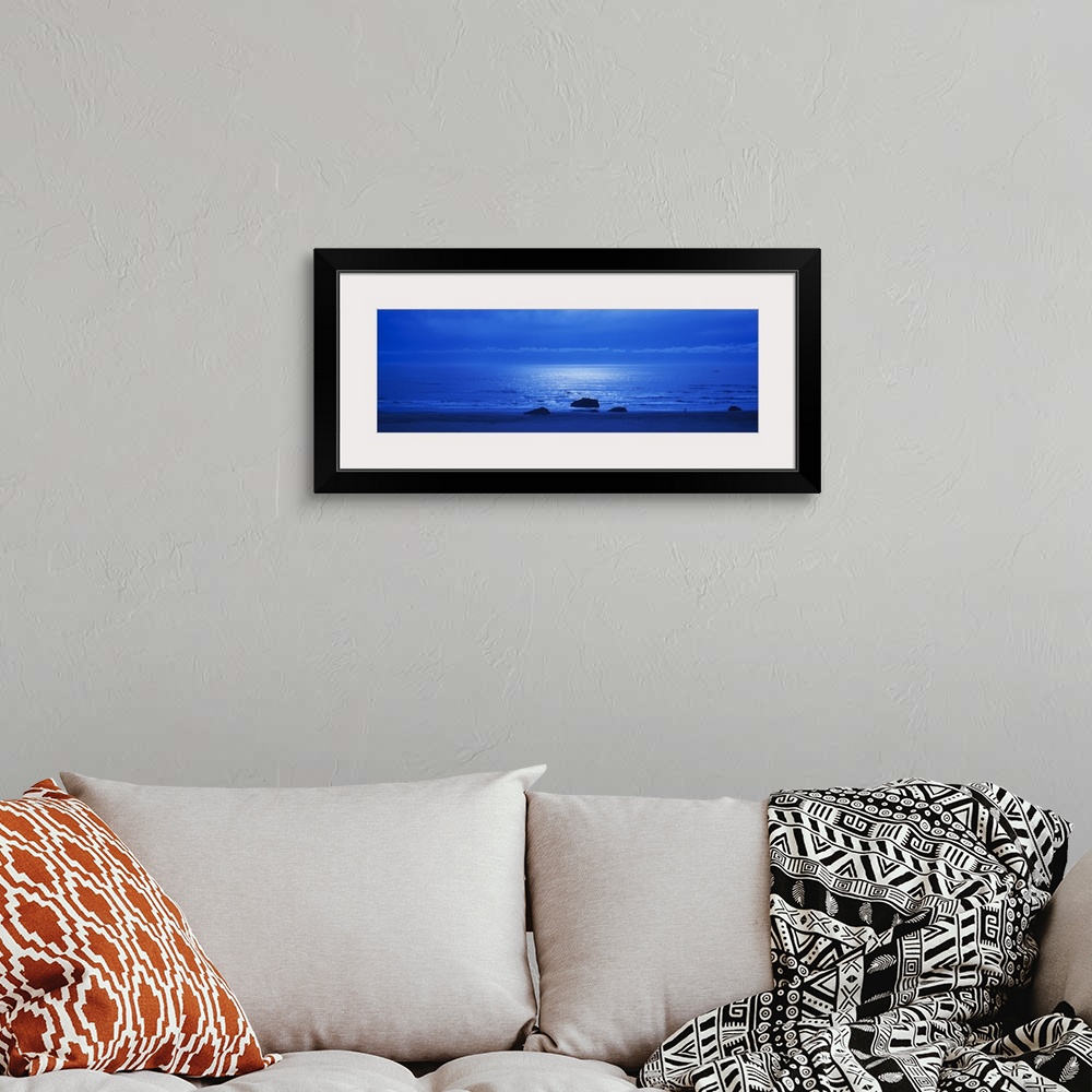 A bohemian room featuring Panoramic photograph of a monotone seascape with the moonlight reflecting off the waves, three so...