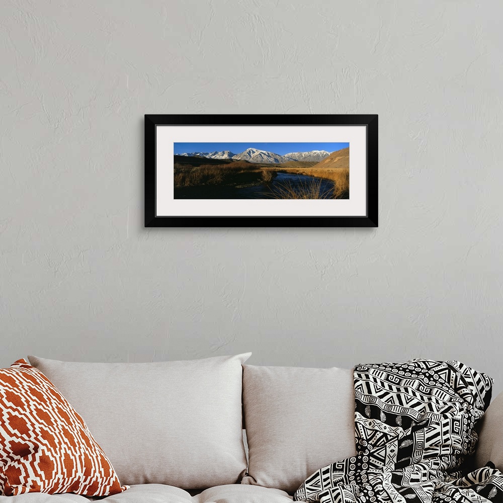 A bohemian room featuring A mountain range lines the background of this panoramic photograph with a river in the foreground...