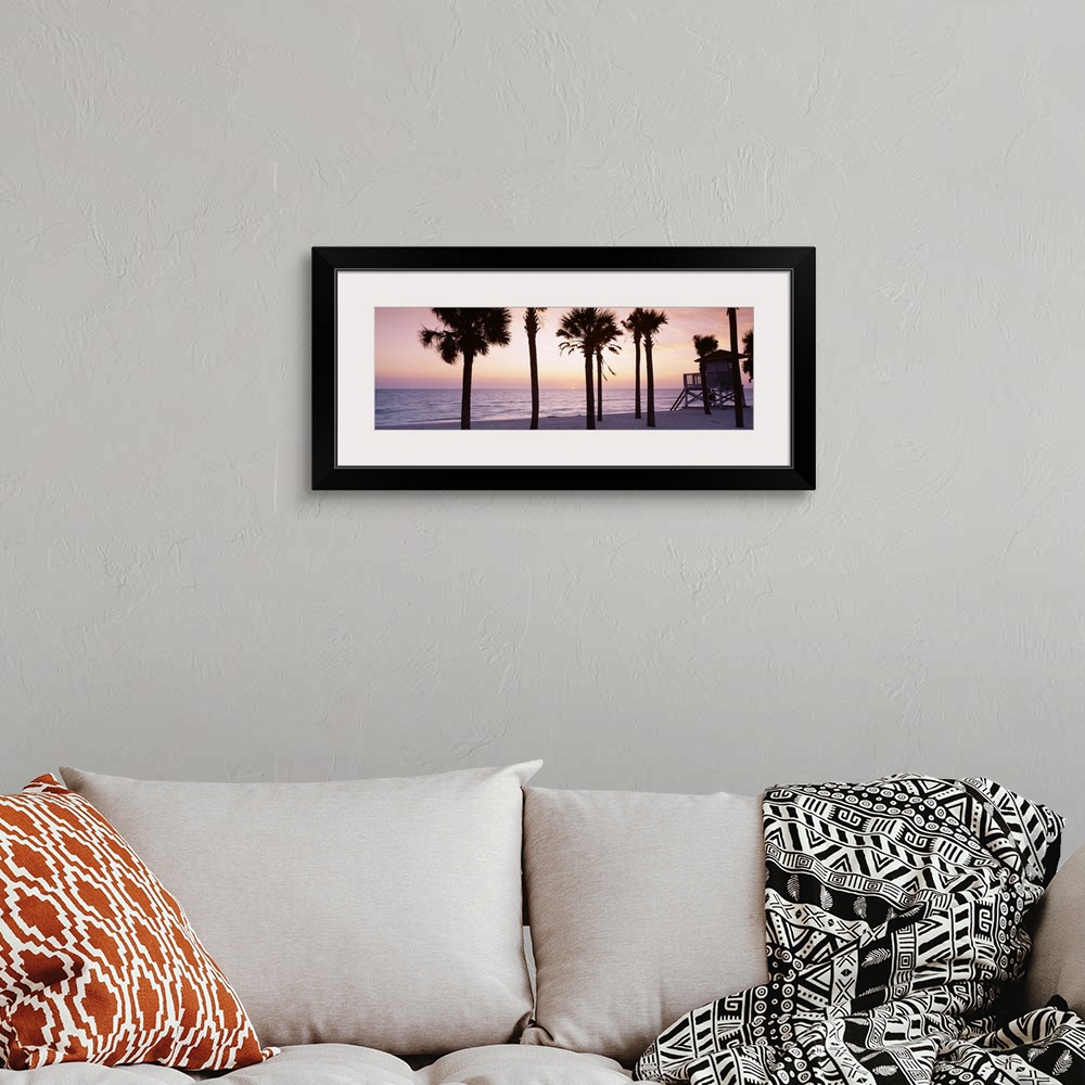 A bohemian room featuring Panoramic photograph taken of palm trees on a beach with the sun just setting below the ocean hor...