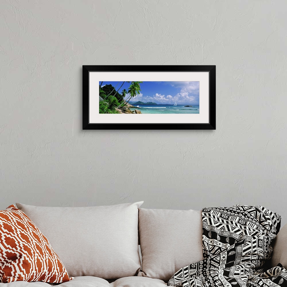 A bohemian room featuring Long panoramic image of palm trees lining a beach with a sailboat sailing in the ocean.
