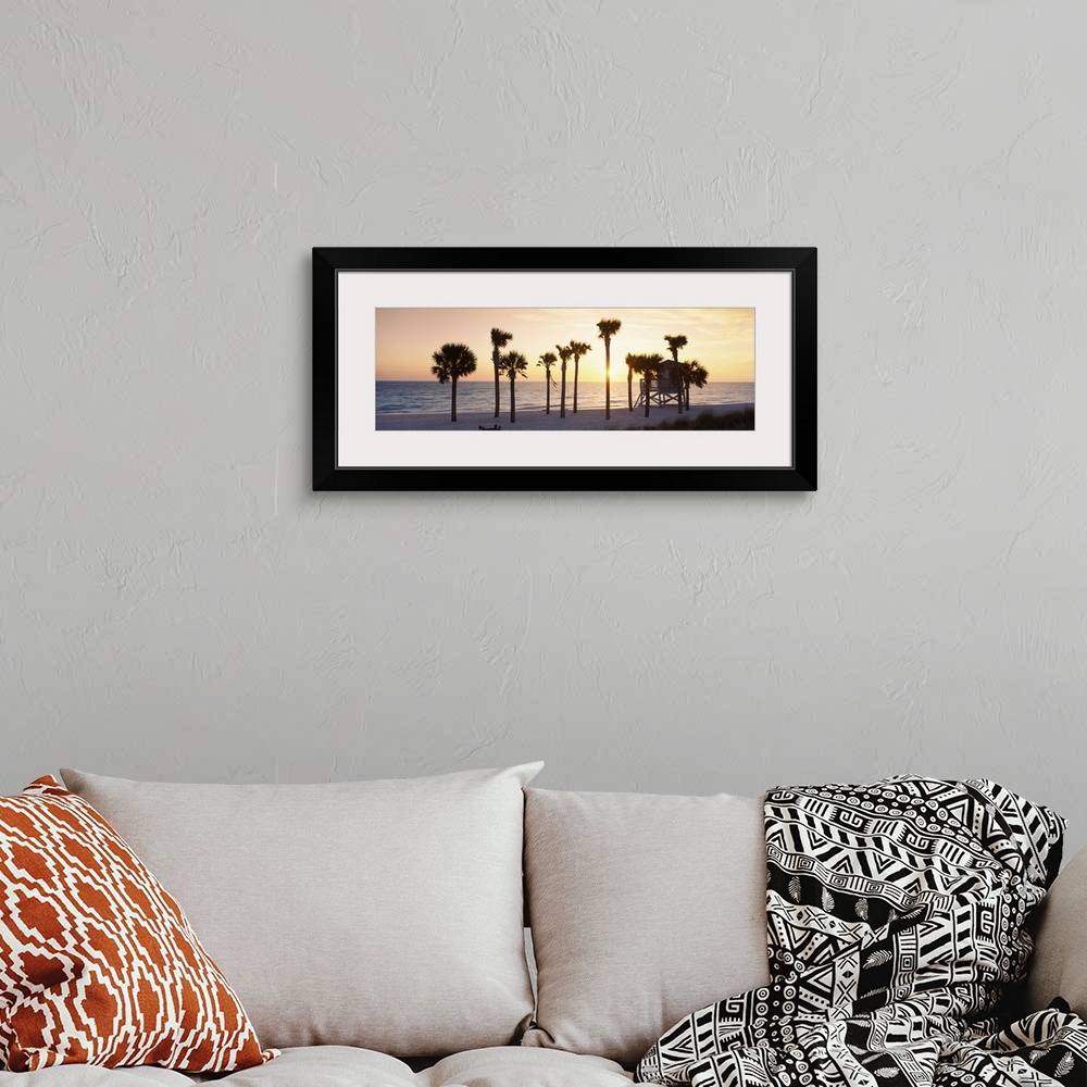 A bohemian room featuring A large panoramic piece of palm trees on the beach with a lifeguard house in front of them. The o...