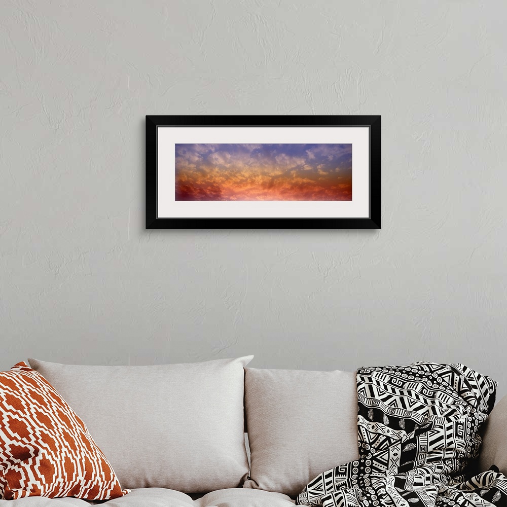 A bohemian room featuring Panoramic photograph of colorful clouds illuminated by the sun.
