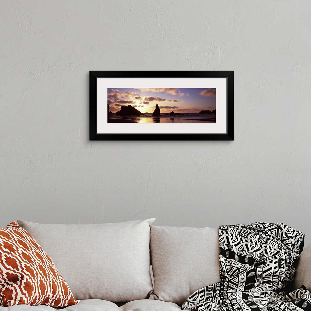 A bohemian room featuring Photo of the sun setting behind rock formations sticking up in the shallow waters of the ocean cr...