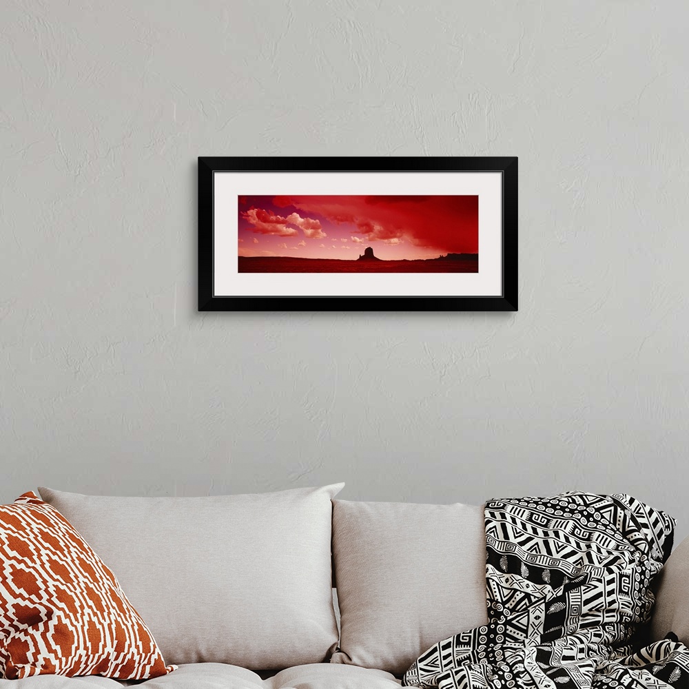 A bohemian room featuring Giant horizontal photograph of a desert landscape beneath a vibrant sky with billowing clouds, a ...