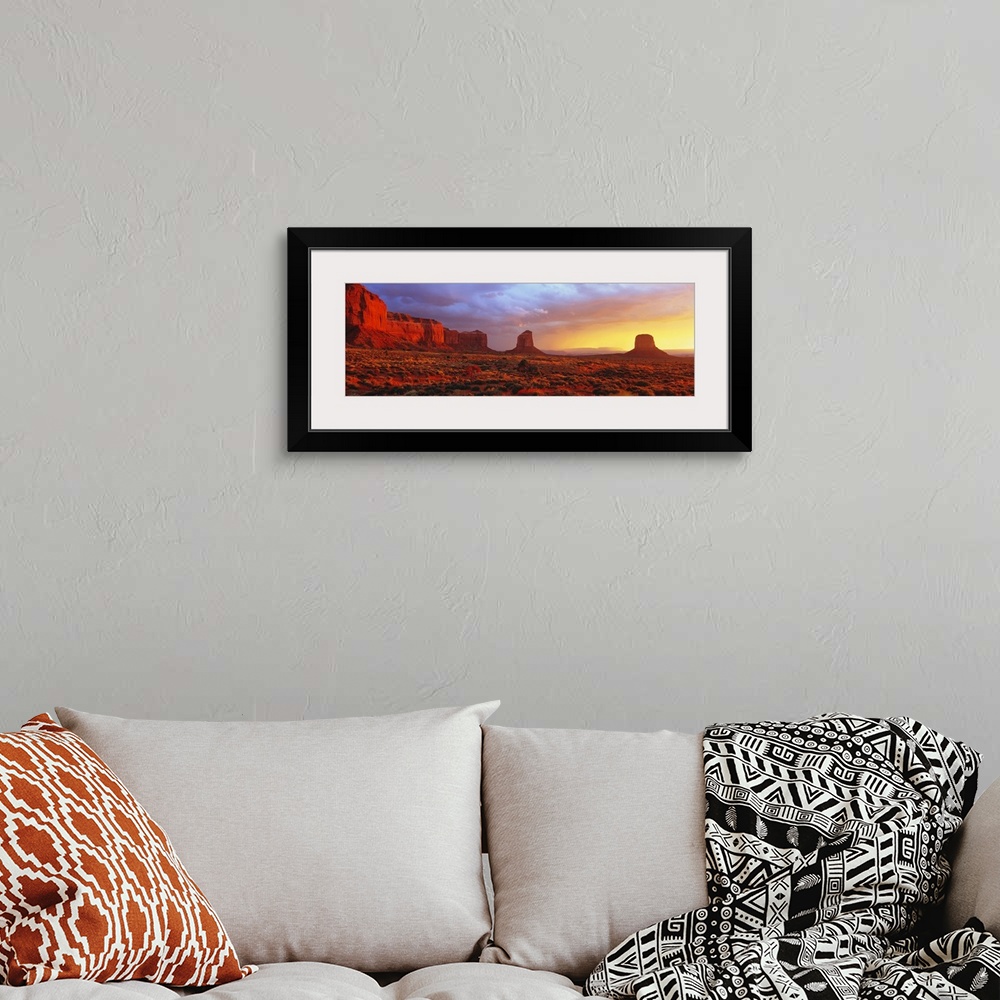 A bohemian room featuring Large panoramic canvas of a desert scene with steep rugged terrain and rock structures at sunrise.