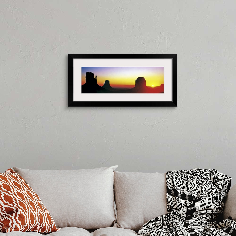 A bohemian room featuring The sun begins to rise and silhouette Monument Valley in a wide angle view.