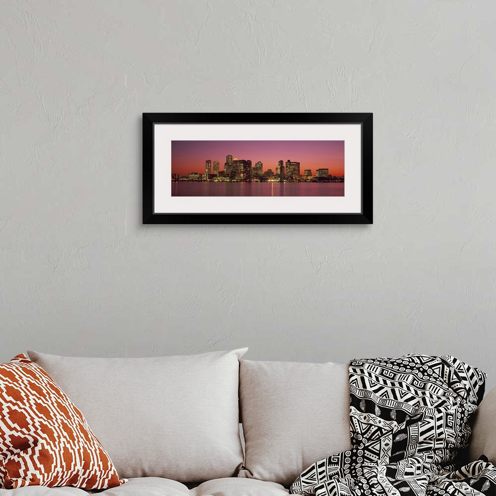 A bohemian room featuring A Massachusetts city lights up at twilight over its blurred reflection in the waters of the bay.