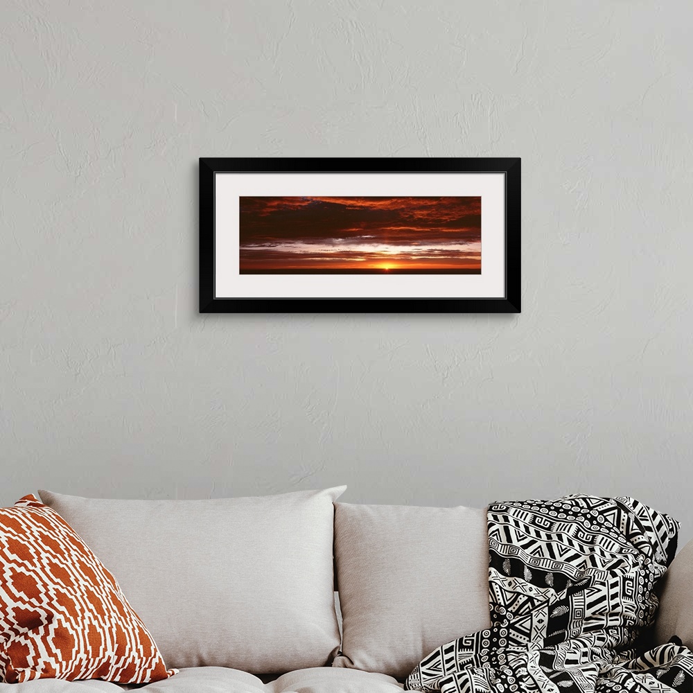 A bohemian room featuring Panoramic photograph of a sunset just hitting the horizon and lighting up a cloud filled sky with...