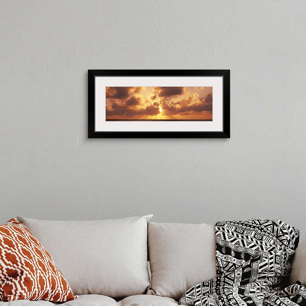 A bohemian room featuring Large panoramic photograph taken of a sunset behind the clouds with its rays bursting through and...