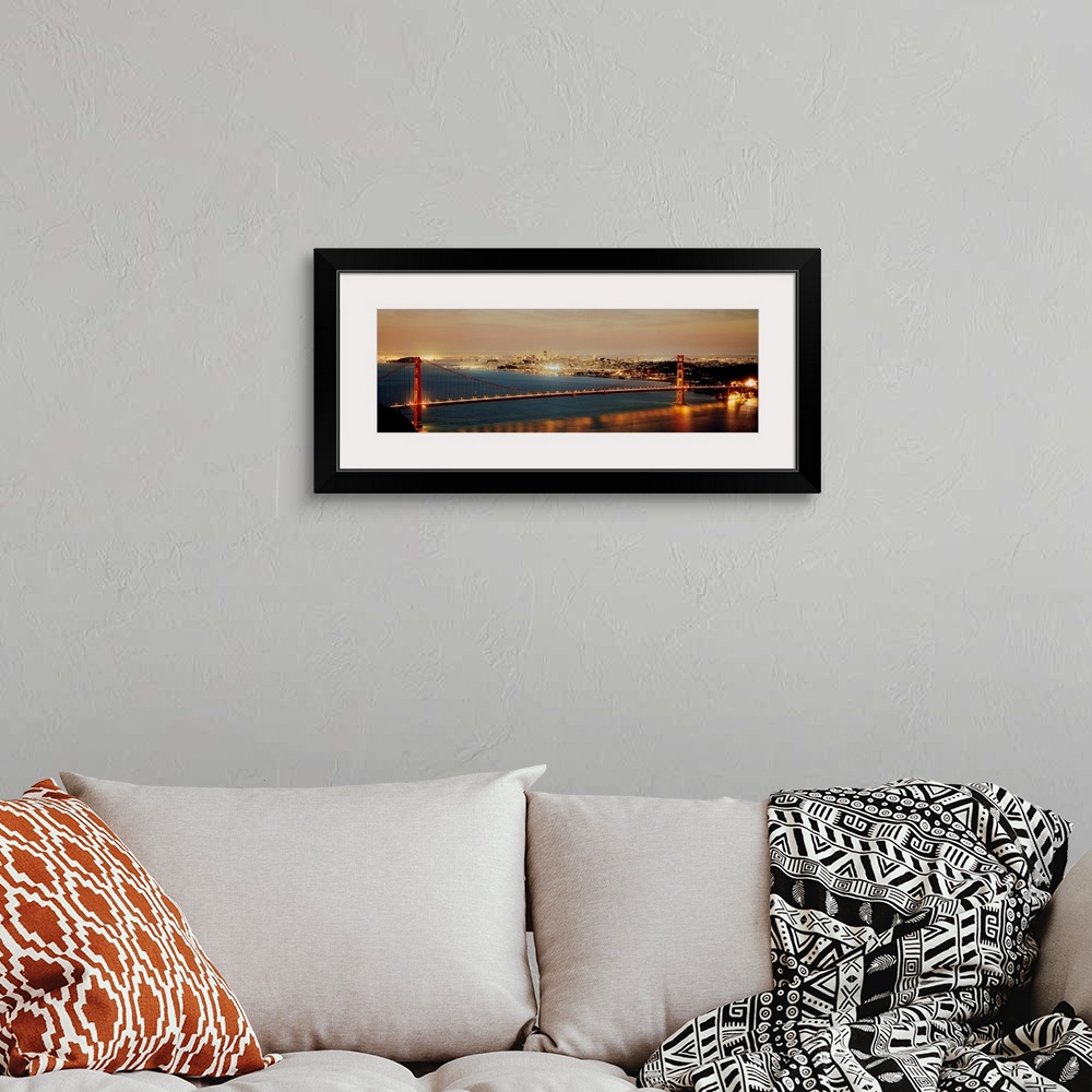 A bohemian room featuring Panoramic photograph shows the bright lights of the Golden Gate bridge as they reflect onto the w...