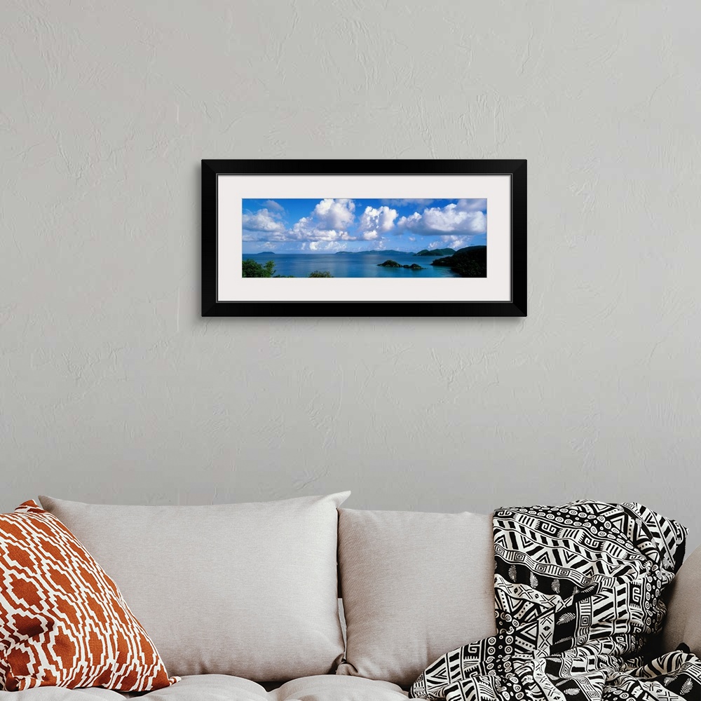 A bohemian room featuring Panoramic photograph of ocean sprinkled with small grass covered islands under a cloudy sky.
