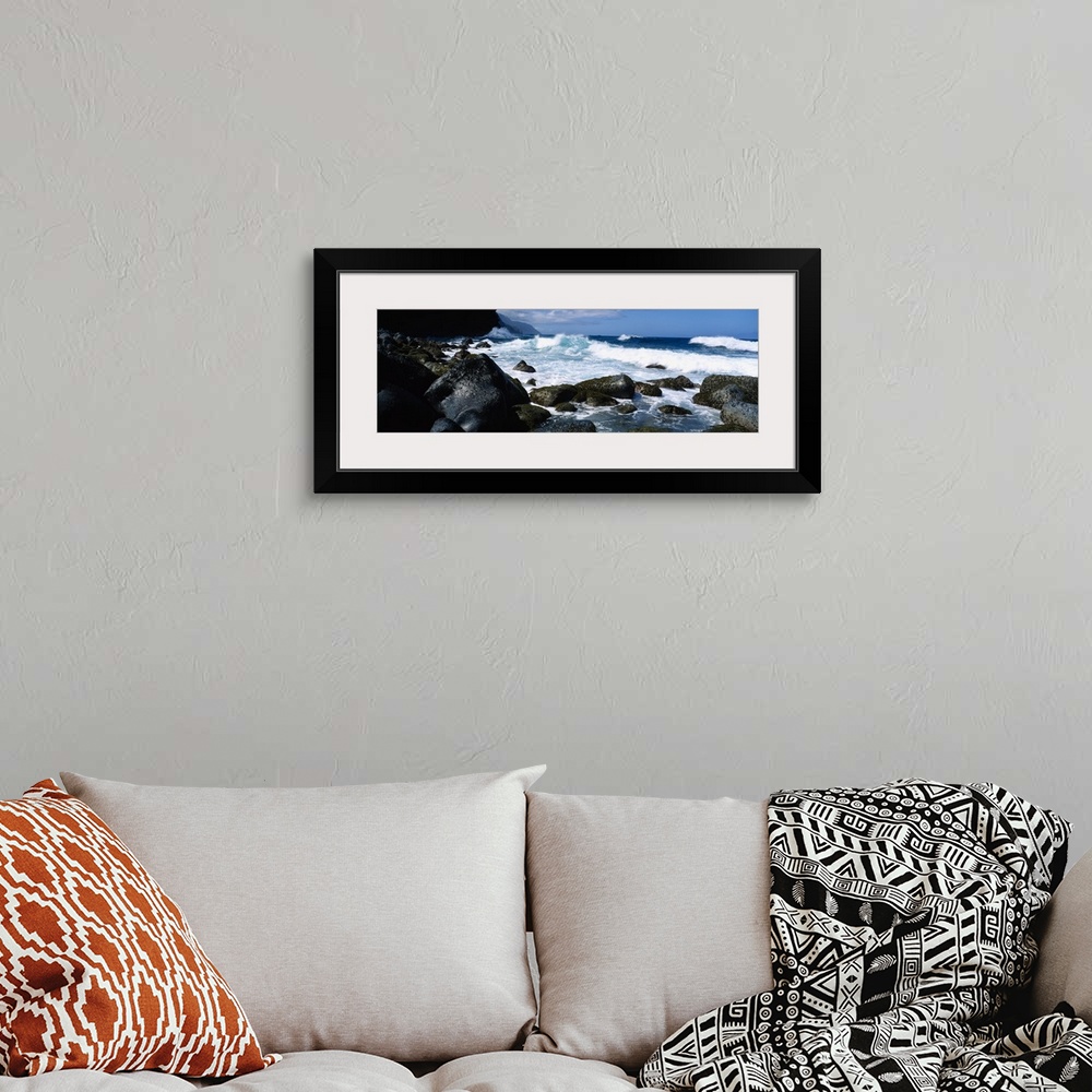 A bohemian room featuring Panoramic photograph on a big canvas of waves crashing onto large rocks along the coast of Na Pal...