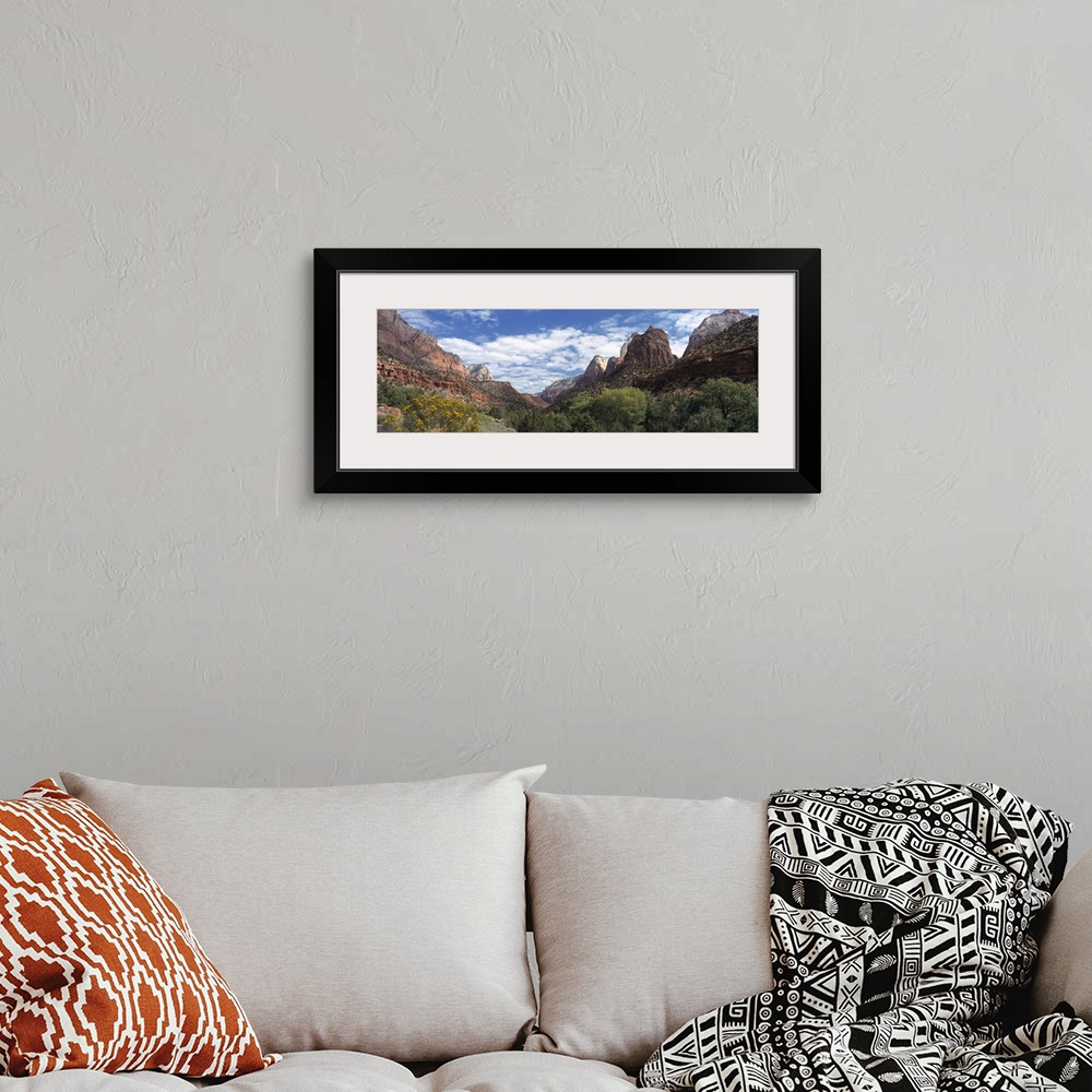 A bohemian room featuring Panoramic photograph of canyon under a cloudy sky with dense shrubbery in the foreground.