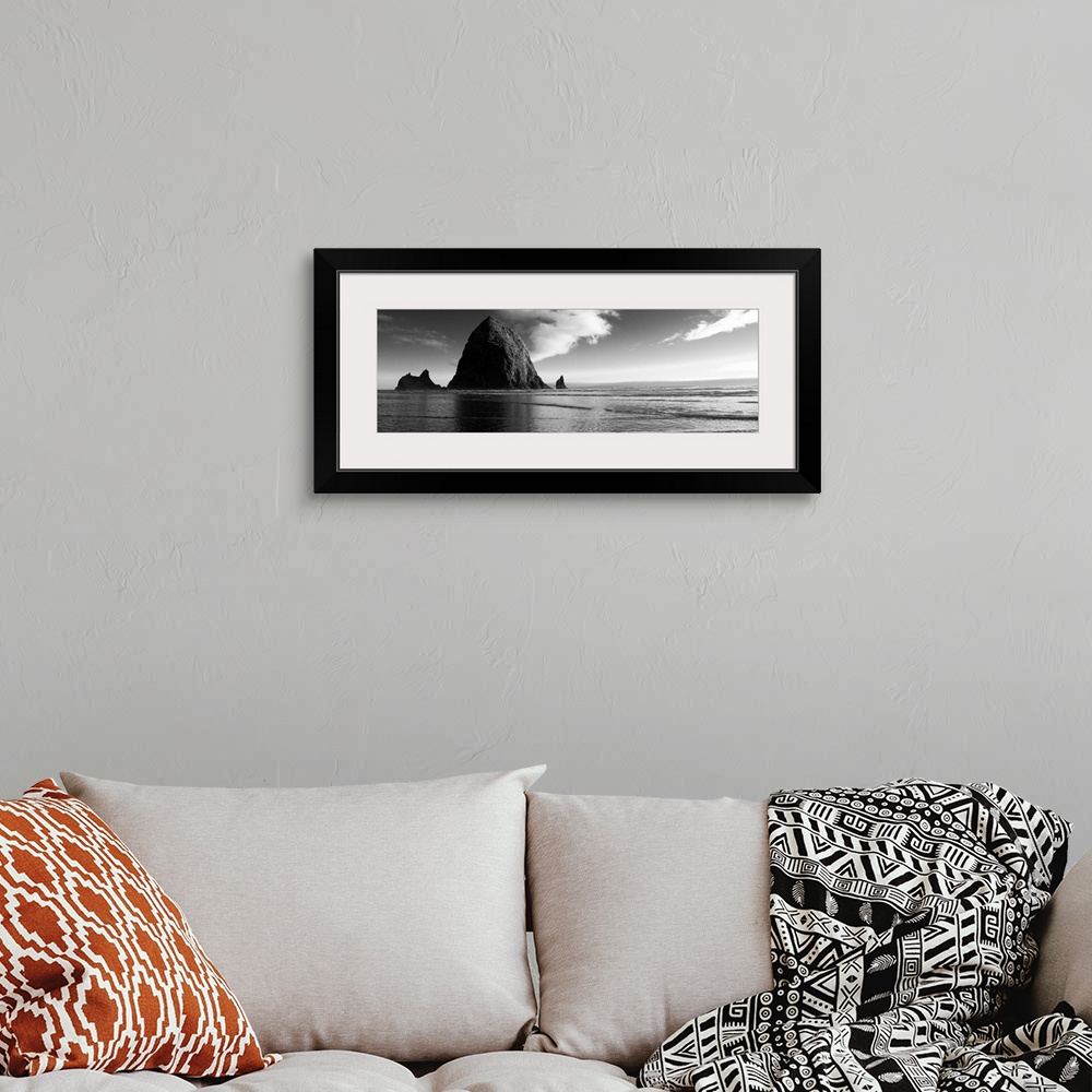 A bohemian room featuring Black and white panoramic photograph of Haystack Rock with rippling waters.