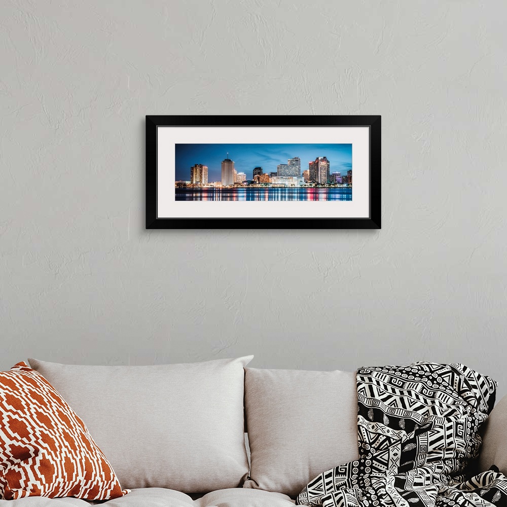 A bohemian room featuring Panoramic photograph of the New Orleans skyline lit up at dusk and reflecting colorful bands onto...