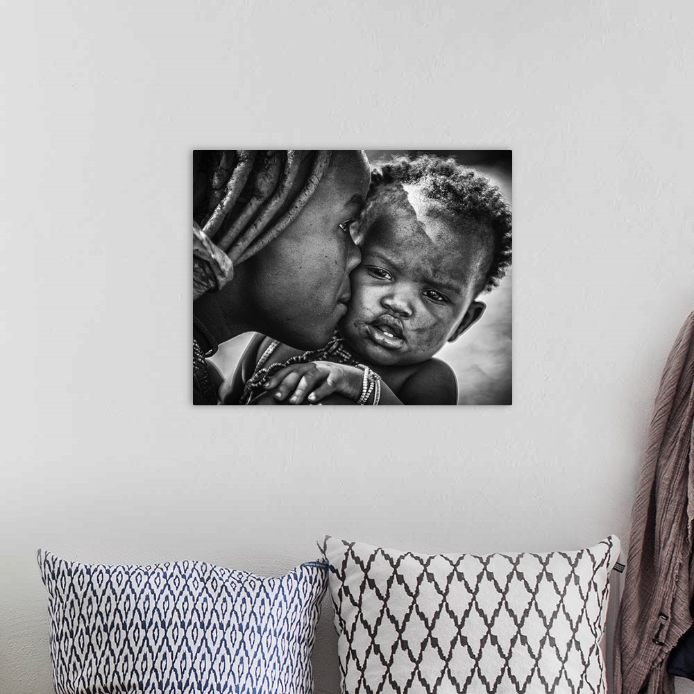 A bohemian room featuring A young boy pulls a funny face as his mother kisses him, Namibia.