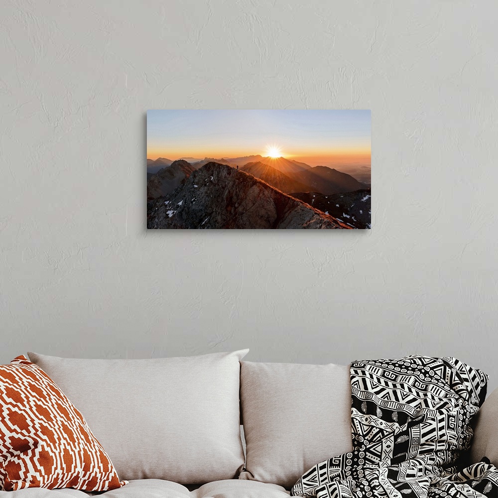 A bohemian room featuring A man running on the ridge of a mountain as the sun rises over the peaks, Stol, Slovenia.