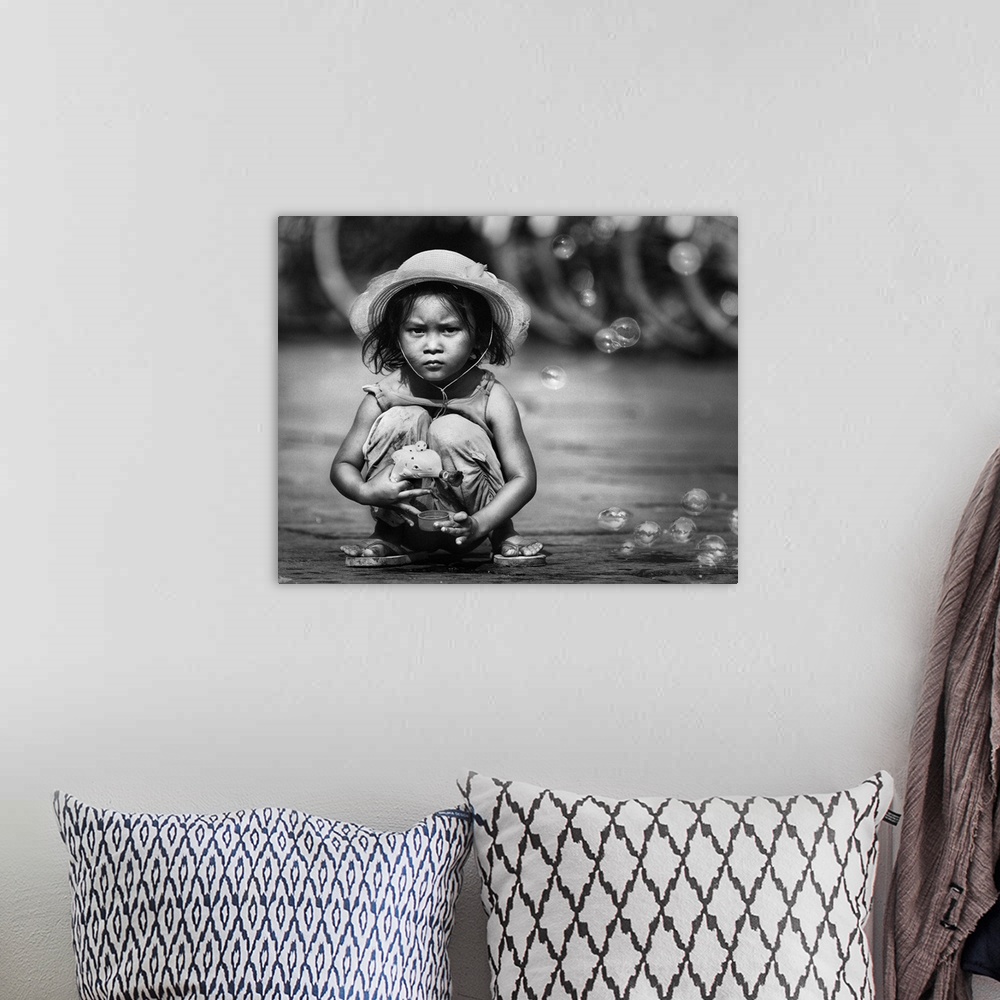 A bohemian room featuring Portrait of a young Indonesian girl playing in the street with a bubble gun.