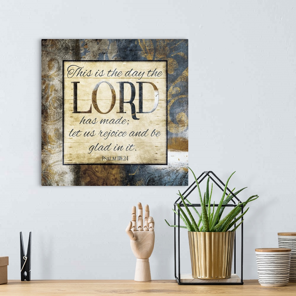 A bohemian room featuring Typography art of the Bible verse Psalm 118:24 framed with classic style gold and blue flourishes.