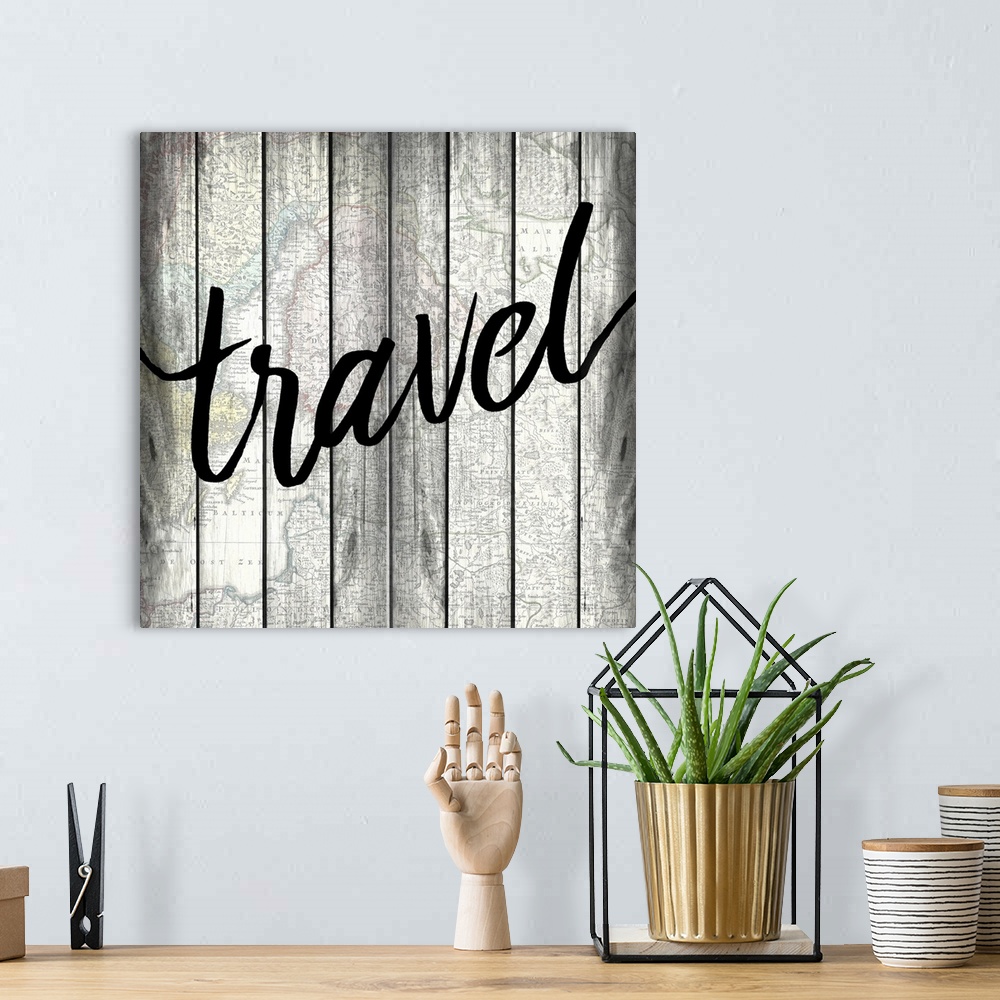 A bohemian room featuring The word ?travel? painted on a wood panel background with an overlay of a map.�