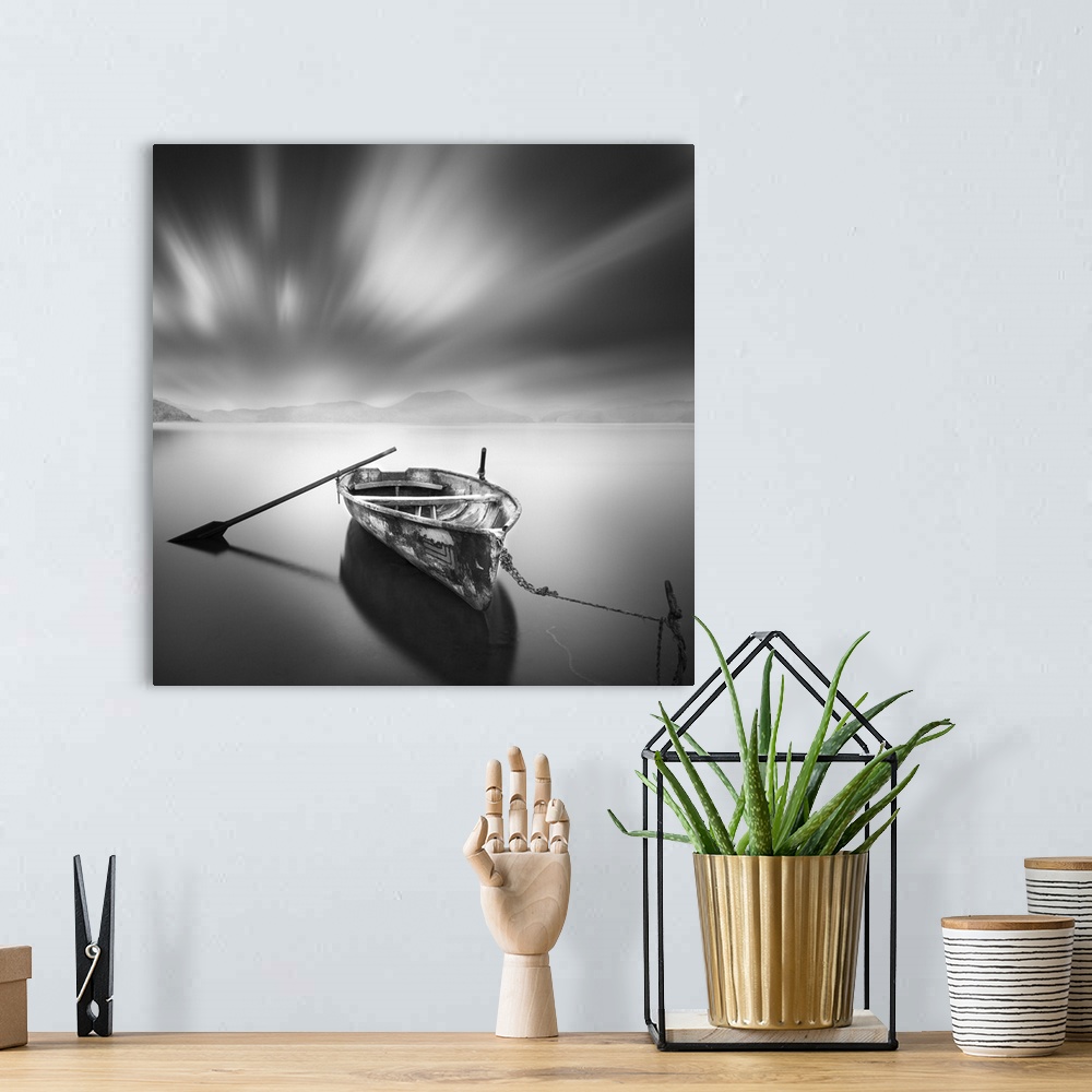 A bohemian room featuring An artistic black and white photograph of a lone and unattended rowboat on a still watery surface...