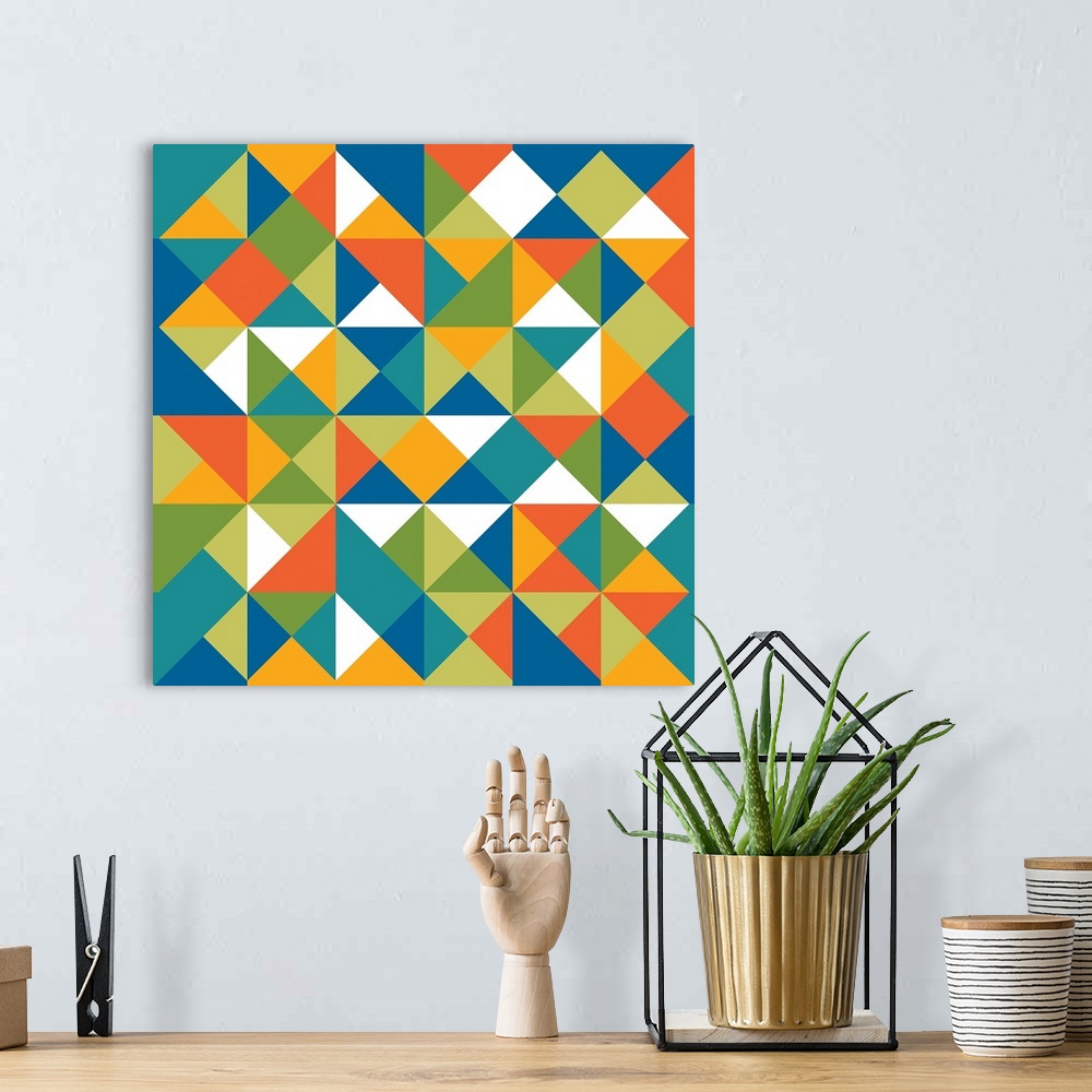 A bohemian room featuring Square geometric art with a triangular pattern in shades of blue, green, orange, yellow, and white.