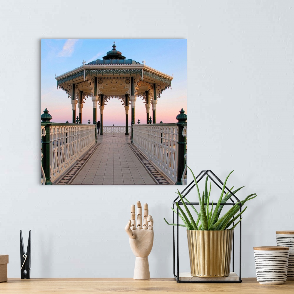 A bohemian room featuring A lone figure and an almost symmetrical shot of an ornate seaside bandstand. The sky is awash wit...