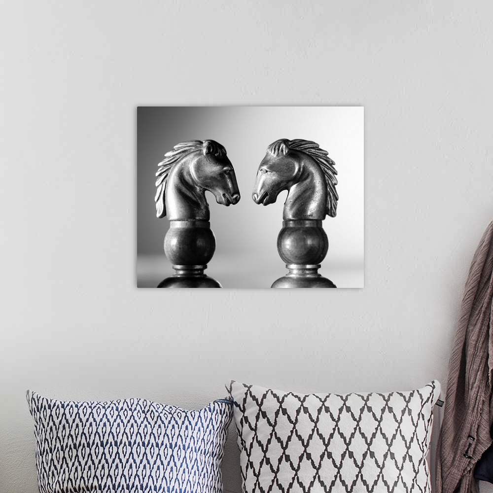 A bohemian room featuring Two chess knights facing off.  Profile shots of two horses in a chess game.