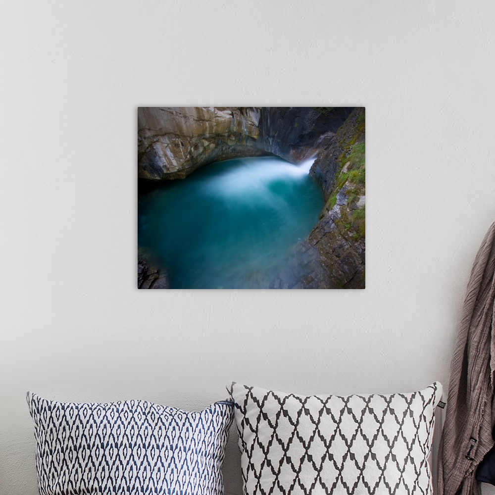 A bohemian room featuring Johnson Canyon, Banff National Park, Canada.  The base of a waterfall flowing into a turquoise pool.