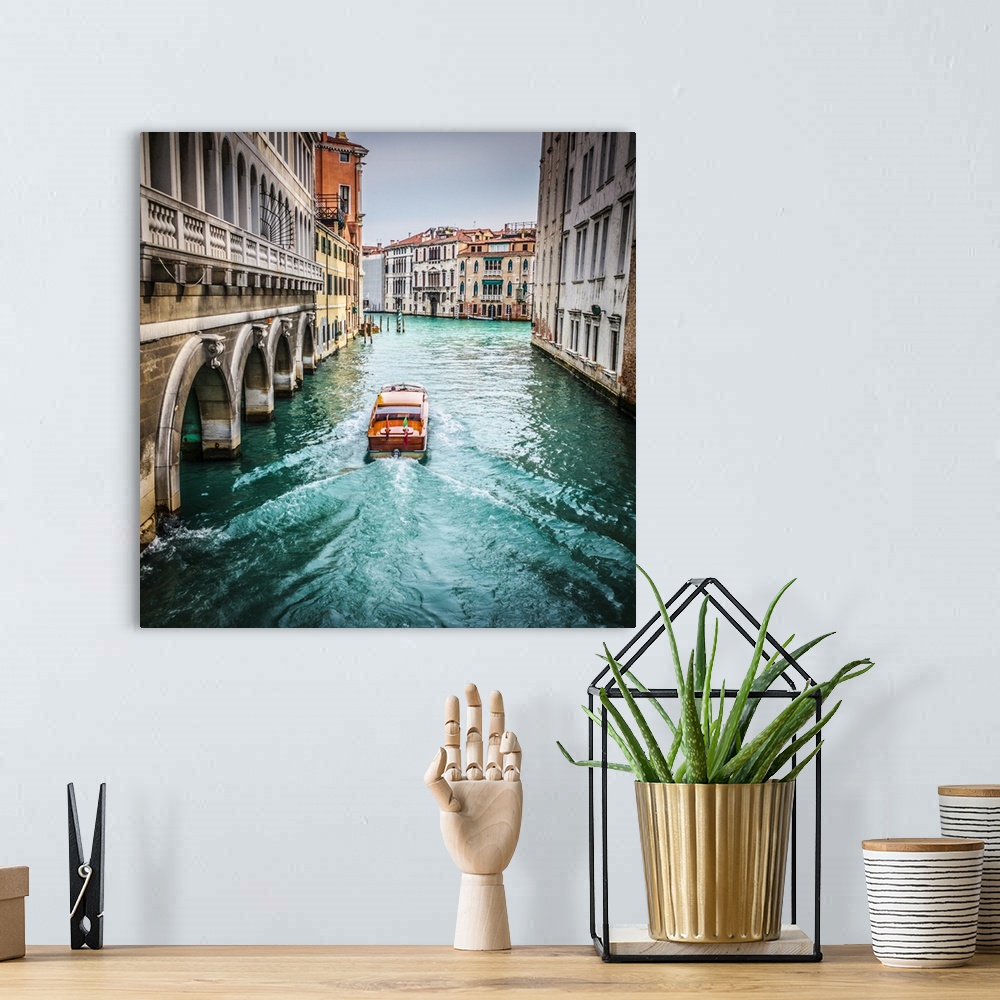 A bohemian room featuring water taxi in a side canal of Venice about to join the Grand Canal.