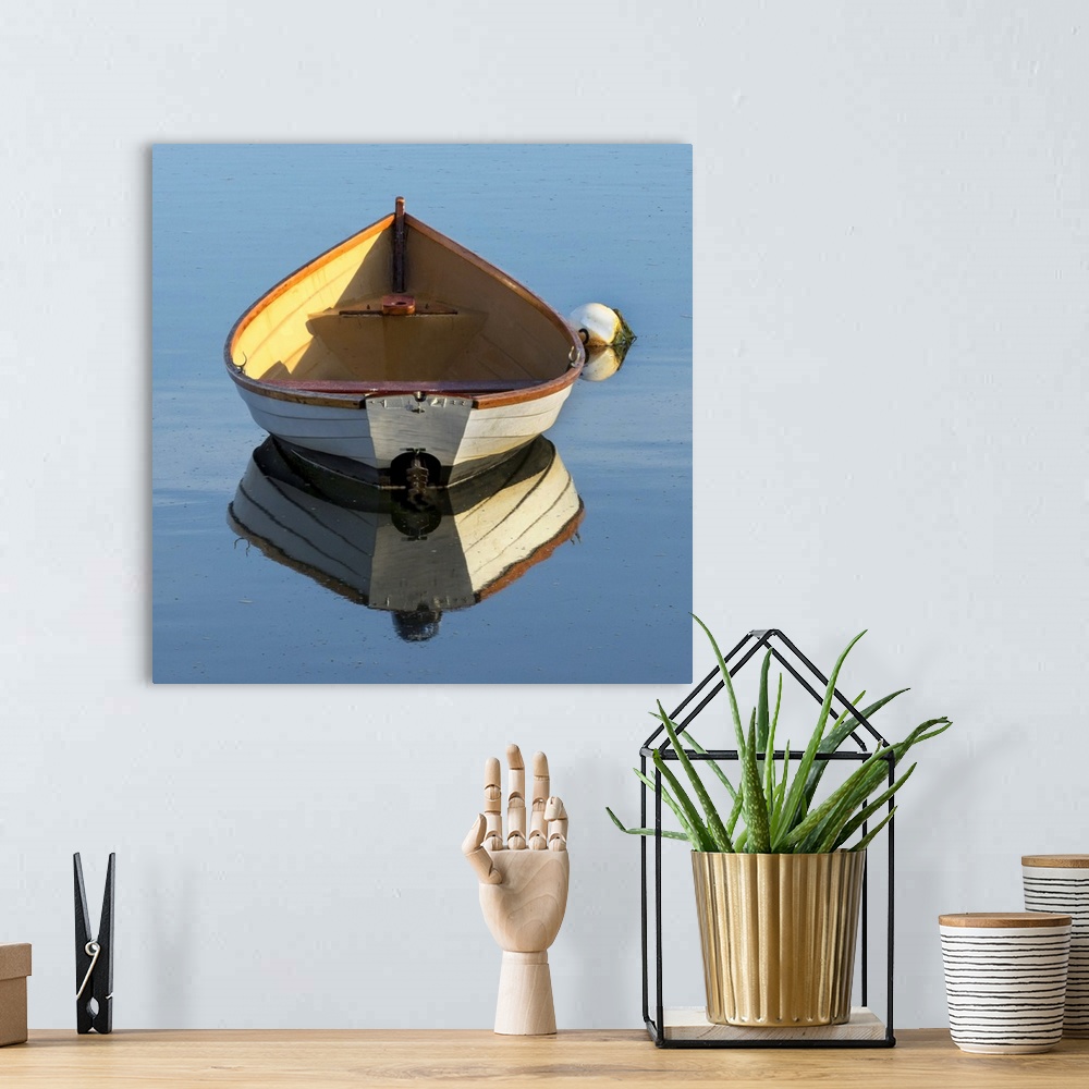 A bohemian room featuring beautiful wooden skiff (boat, dinghy) photographed from the back with a reflection in water - a b...