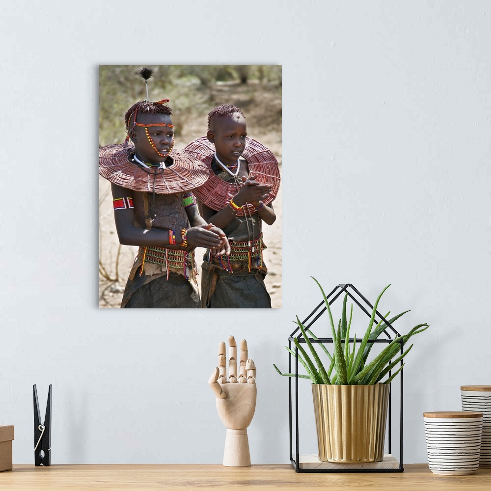 A bohemian room featuring Two young Pokot girls wearing traditional ornaments that denote their unmarried status. Their bro...
