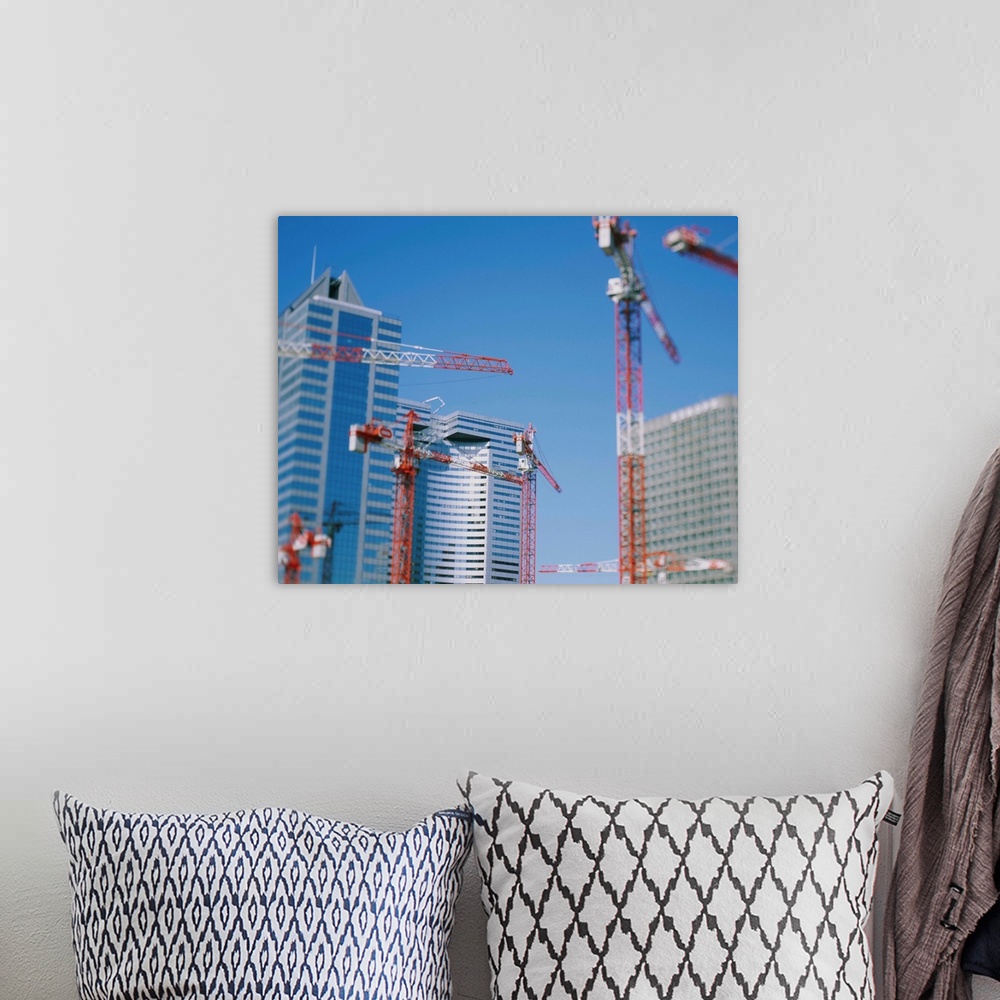 A bohemian room featuring Low angle view of cranes in front of buildings
