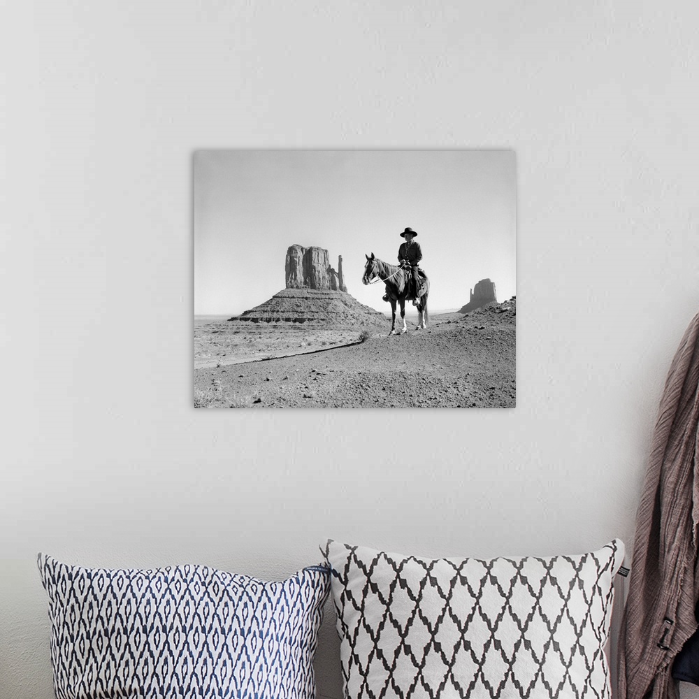 A bohemian room featuring Navajo indian in cowboy hat on horseback with monument valley rock formations in background.