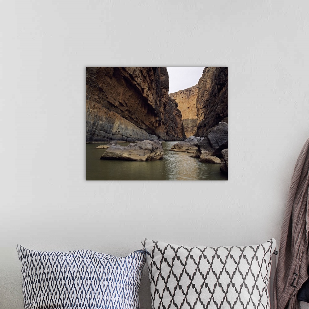 A bohemian room featuring Photo print of a rugged canyon with water flowing by big rocks at the bottom.