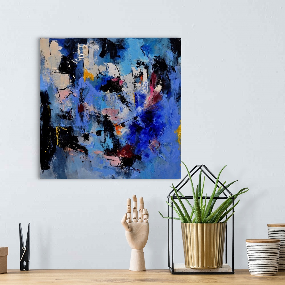 A bohemian room featuring A square abstract painting in dark shades of black, blue, white and pink with splatters of paint ...