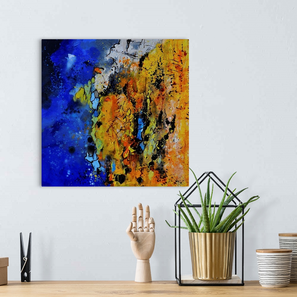 A bohemian room featuring A square abstract painting with vibrant colors of blue, orange and yellow.