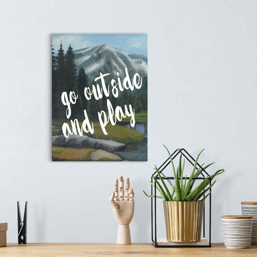 A bohemian room featuring White handlettered text reading "Go outside and play" over a painting of a mountain landscape.