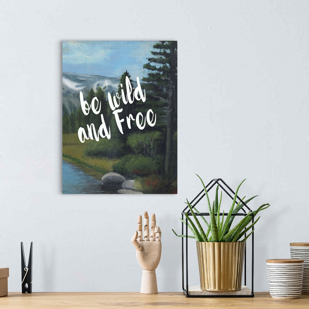 A bohemian room featuring White handlettered text reading "Be wild and free" over a painting of a mountain landscape.
