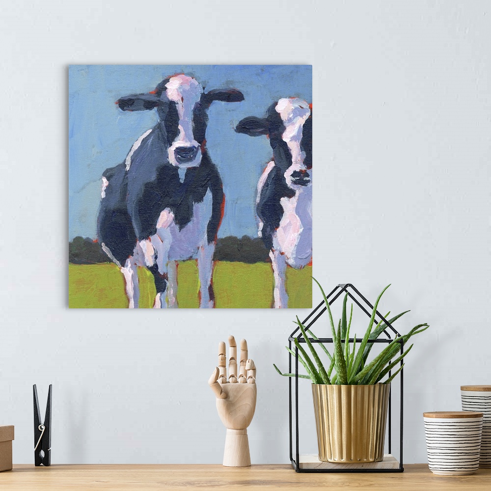 A bohemian room featuring Contemporary painting of two black and white dairy cows in a green field.