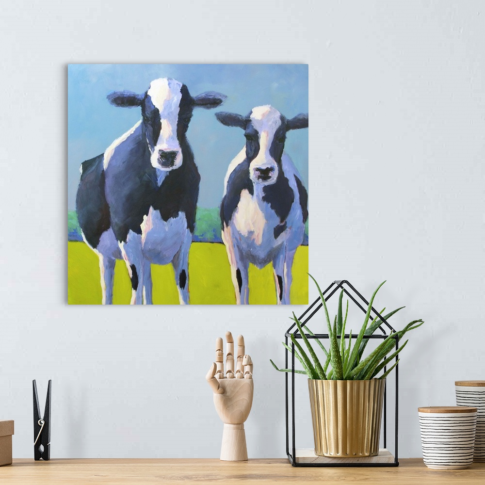 A bohemian room featuring Contemporary painting of two black and white dairy cows in a green field.