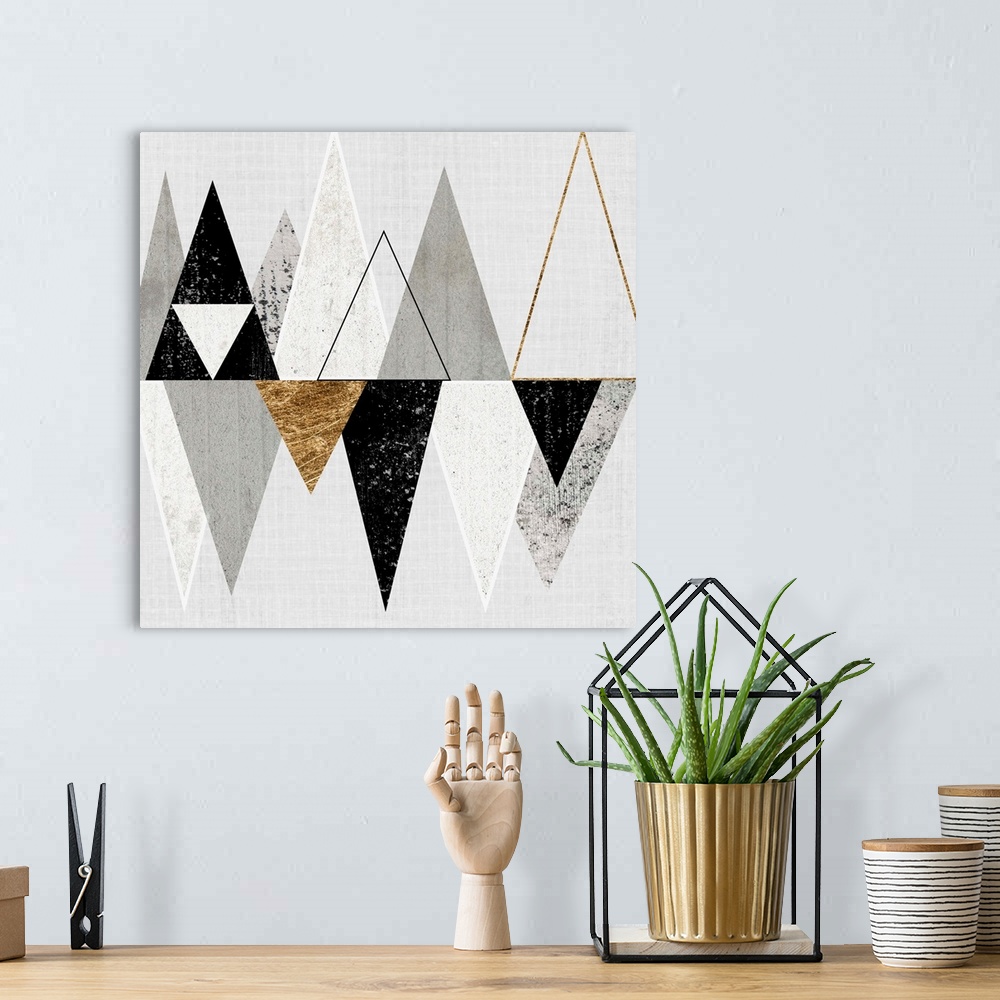A bohemian room featuring Abstract art of two rows of triangles in black, grey, and gold.